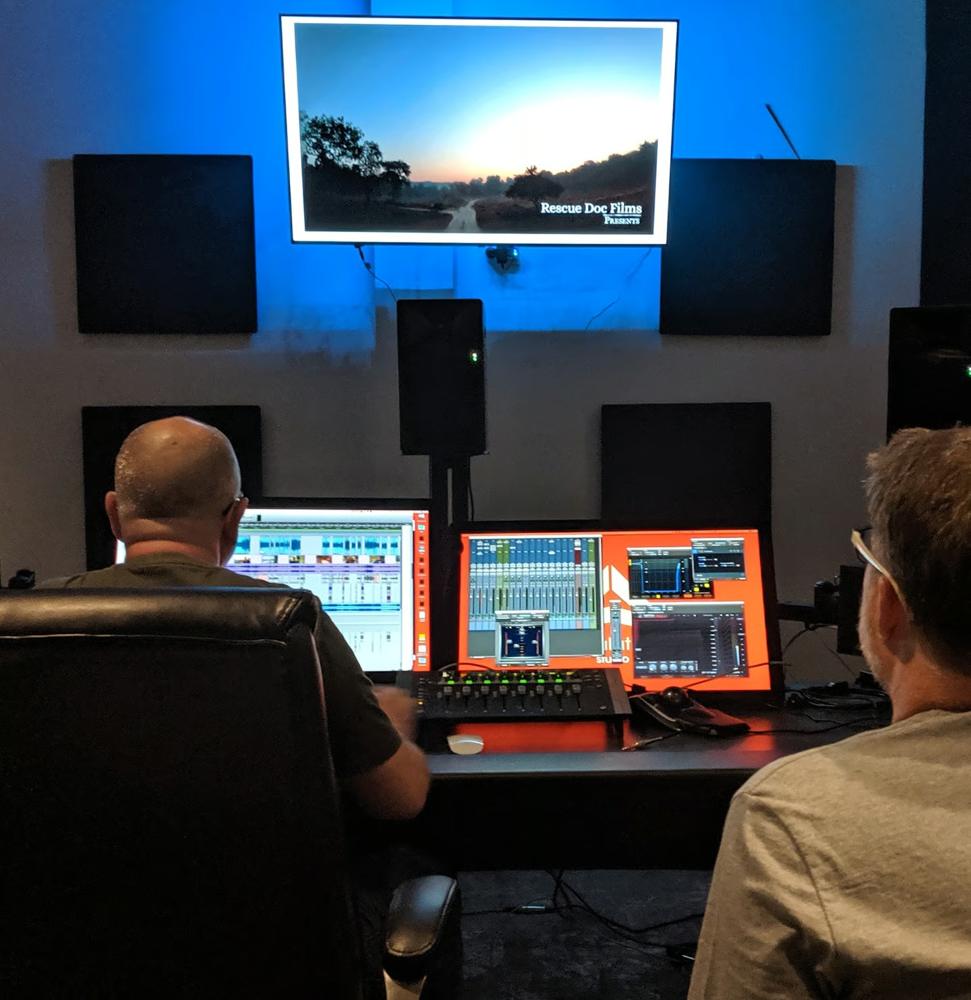 Mixing sound at a console in front of a large screen
